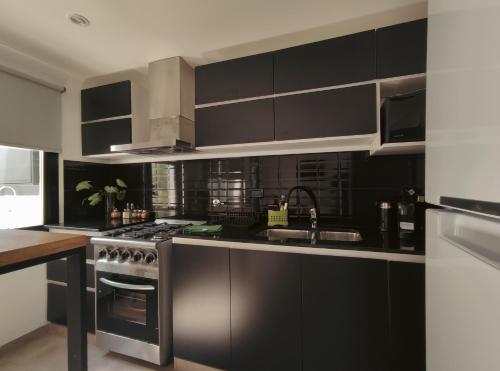 una cocina con armarios negros y electrodomésticos de acero inoxidable en 4 de Abril Dpto - by Me Nomad en Tandil