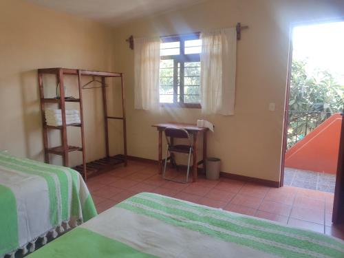 une chambre avec deux lits, une table et une fenêtre dans l'établissement Casa Cora Oaxaca Hospedaje Familiar Guesthouse Casa de Huespedes, à Oaxaca
