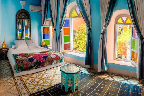 a bedroom with a bed and two windows at Riad Persephone in Marrakesh