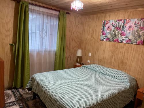a bedroom with a bed and a window with green curtains at Casa frente a la playa in Valdivia