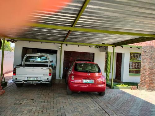 a red car and a white truck parked in a garage at Kea bed and breakfast in Mogwase