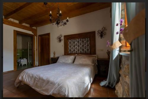a bedroom with a bed and a chandelier at Hotel Rural en Las Cascadas de Tobera in Tobera