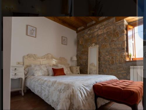 a bedroom with a large bed and a stone wall at Hotel Rural en Las Cascadas de Tobera in Tobera