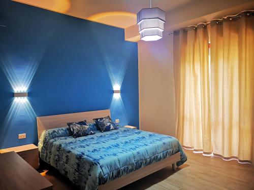 a bedroom with blue walls and a bed with two pillows at Residenza Nemi con balcone vista mare - porto in Vibo Valentia Marina