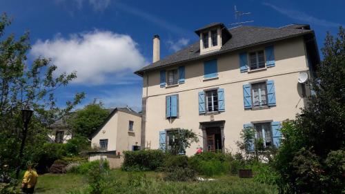 a white house with blue windows and a chimney at LES ANDALOUSES in Avèze