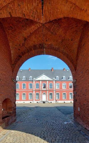 a large brick building with an arch in front of it at Paddock Lodge - Suites Wellness & Chambres d'hôtes in Stoumont