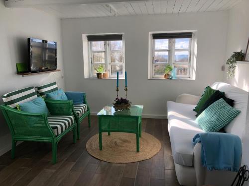 a living room with green chairs and a white couch at Beachhouse Langeland in Tranekær