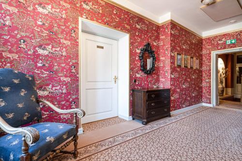 a room with red floral wallpaper and a blue chair at Padise Manor in Padise