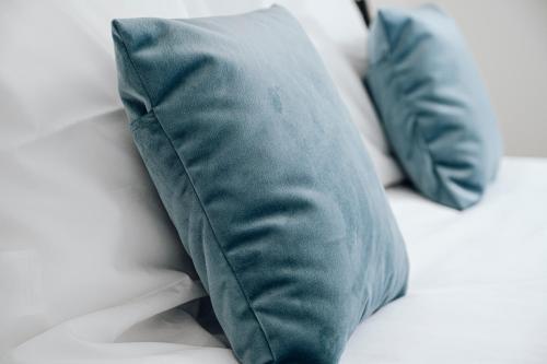 two blue pillows sitting on a white bed at Vakantiehuis Spoor 74 in Diksmuide