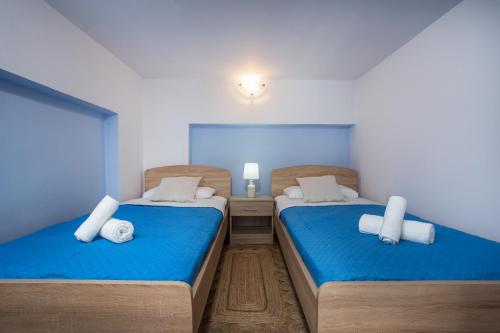 two beds in a room with blue sheets at Haraki Bay Loft (by haris) in Haraki