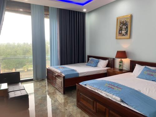 a bedroom with two beds and a large window at Khách sạn Nghinh Phong Beach Tuy Hòa in Tuy Hoa