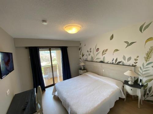 a bedroom with a white bed and a window at Hôtel Le Colombier in Moustiers-Sainte-Marie