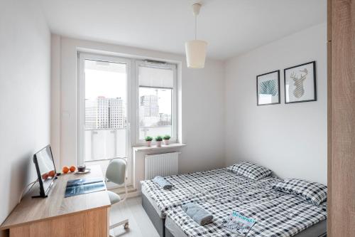 a bedroom with a bed and a desk and window at Pokoje Wita Stwosza in Warsaw