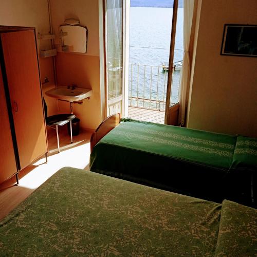 a bedroom with two beds and a window with a view at Affittacamere Trattoria Della Cascata in Oggebbio