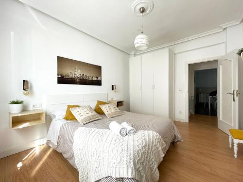 a white bedroom with a large bed with two towels at LORE - Parking y bicis gratis in San Sebastián