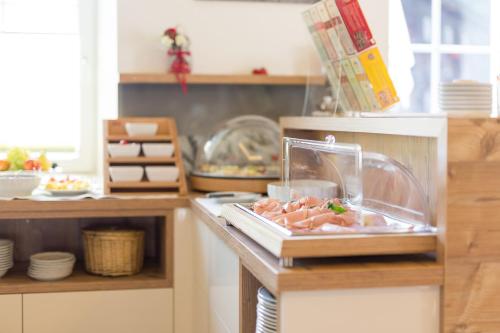 a kitchen with a counter with meat in a container at Hotel Garni Grünmoos in Sankt Jakob in Defereggen