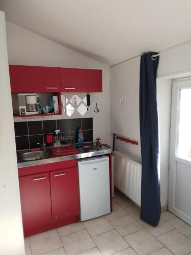 Elle comprend une petite cuisine avec des placards rouges et un évier. dans l'établissement GITE ENTRE TERRE ET MER, à Mareuil-sur-Lay