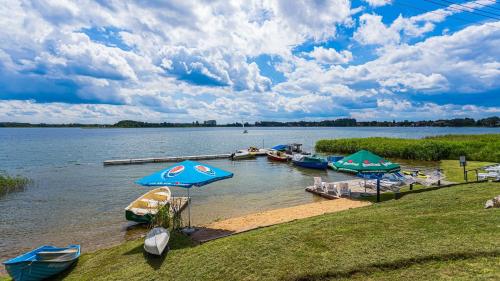 a group of boats docked on a beach with umbrellas at Niebieska Tawerna in Węgorzewo