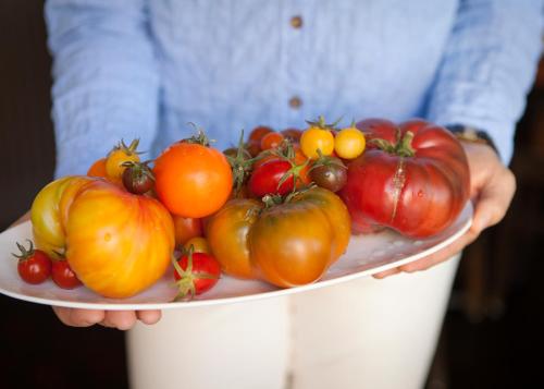 a person holding a plate with tomatoes on it at El Dorado Hotel in Sonoma