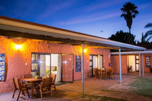 a patio with tables and chairs in front of a building at Culdesac Guesthouse Oudtshoorn in Oudtshoorn