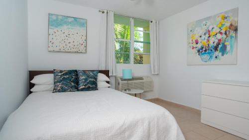 a bedroom with a white bed and two windows at Landing View 304 with rooftop terrace in Rincon