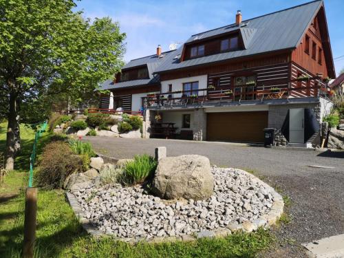 a large house with a rock garden in front of it at Ubytování Kuncovi in Bedřichov