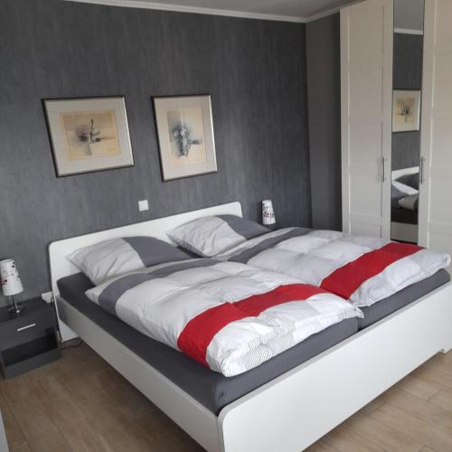 a bedroom with a large bed with white and red sheets at Appartment am Fingerhut in Cloppenburg