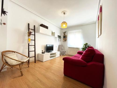 a living room with a red couch and a tv at LORE - Parking y bicis gratis in San Sebastián