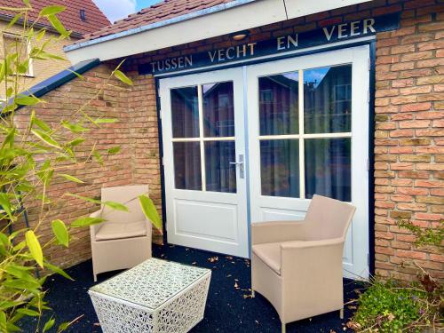 two chairs and a door in front of a building at B&B Tussen Vecht en Veer in Hardenberg
