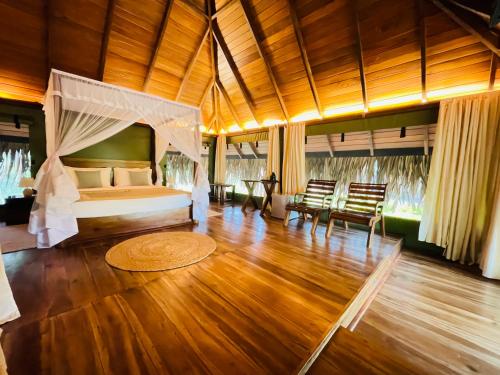 ein Schlafzimmer mit einem Bett und Stühlen in einem Zimmer in der Unterkunft Yala Lake View Cabanas in Tissamaharama