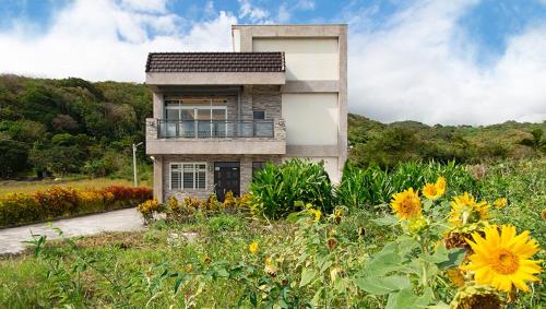 a house on a hill with a field of flowers at 三仙台心悅民宿 in Mei-sha-lu