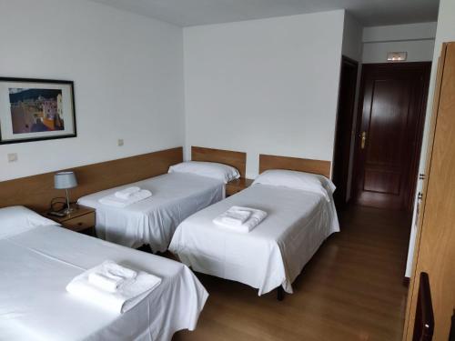 a room with three beds with white sheets at Pensión Las Matillas in Miranda de Ebro