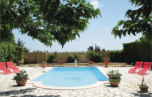 une piscine avec des chaises rouges et une personne debout à côté de celle-ci dans l'établissement Cozy Home In Creissan With Wifi, à Creissan
