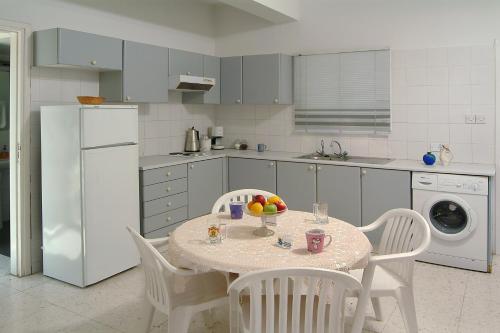a kitchen with a table and chairs and a white refrigerator at Sunbay Apartments in Pyla