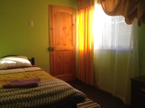 1 dormitorio con cama y ventana con cortina en Cabañas Anakena en Hanga Roa