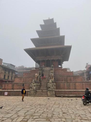 a person standing in front of a large building at Hotel Empire & Rooftop Restaurant in Bhaktapur