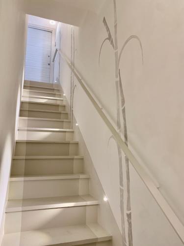 a stairway with white stairs with a plant painted on the wall at Giardino Botanico in Ragusa
