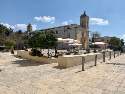 a patio with tables and umbrellas in front of a building at Giardino Botanico in Ragusa