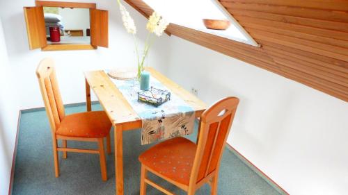 una mesa de madera con 2 sillas y un jarrón. en Ferienwohnung Vogelsang, en Undeloh