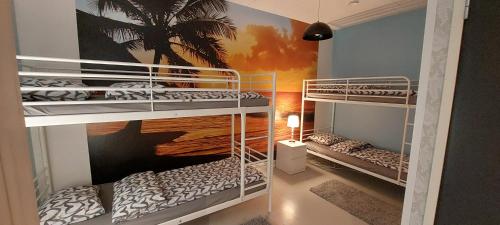 two bunk beds in a room with a palm tree mural at Kontiolomat Oy in Kontioniemi