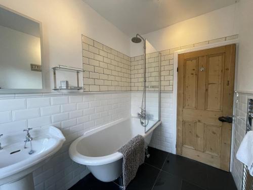 a white bathroom with a tub and a sink at Tawny Cottage in Portinscale
