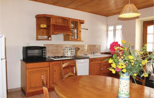 a kitchen with wooden cabinets and a table with a vase of flowers at Awesome Home In St Julien De Peyrolas in Aiguèze
