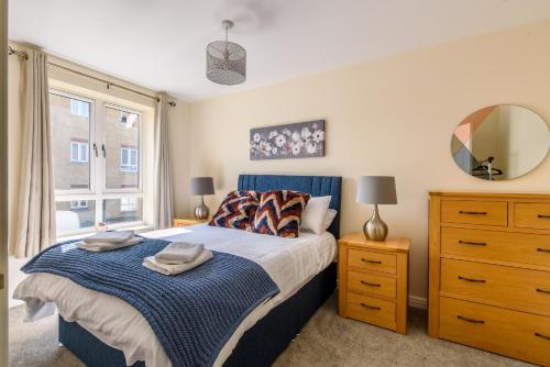 a bedroom with a bed and a mirror and a dresser at Charming & Spacious 3BR With Private Parking Near Ipswich in Ipswich