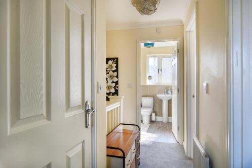 a bathroom with a toilet and a sink and a door at Charming & Spacious 3BR With Private Parking Near Ipswich in Ipswich