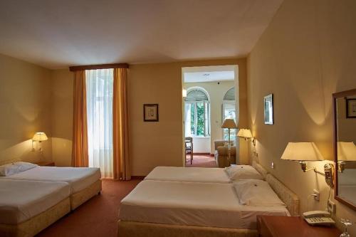 a hotel room with two beds and a mirror at Hotel Vila Ružica- glavna zgrada i depandanse in Crikvenica