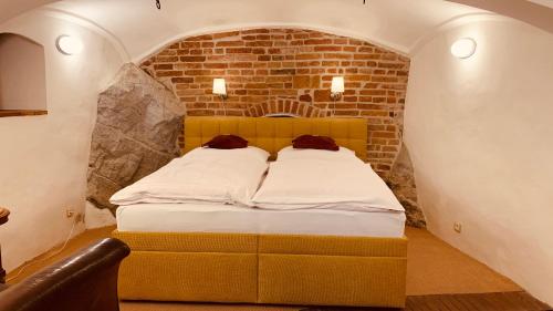 a bed in a room with a brick wall at Penzion Kapr in Český Krumlov