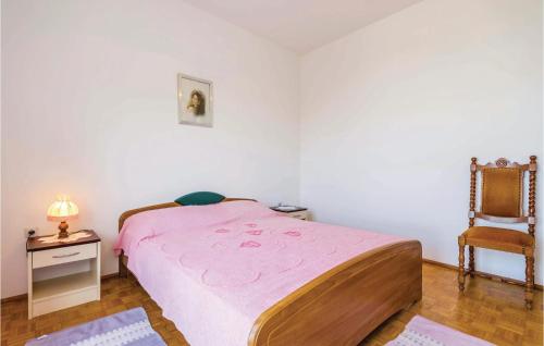 a small bedroom with a pink bed and a chair at Holiday Home Baric Draga Ii in Barić Draga
