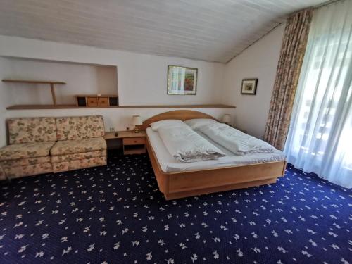 ein Schlafzimmer mit einem Bett und einem Sofa in der Unterkunft Hotel Burgleitenhof in Lana