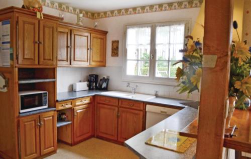 une cuisine avec des armoires en bois, un évier et une fenêtre dans l'établissement Holiday Home Penestin Chemin De Camaret, à Pénestin