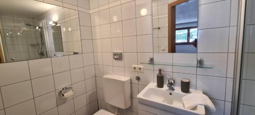 Baño blanco con lavabo y espejo en Ferienwohnung Geismayr en Dornbirn